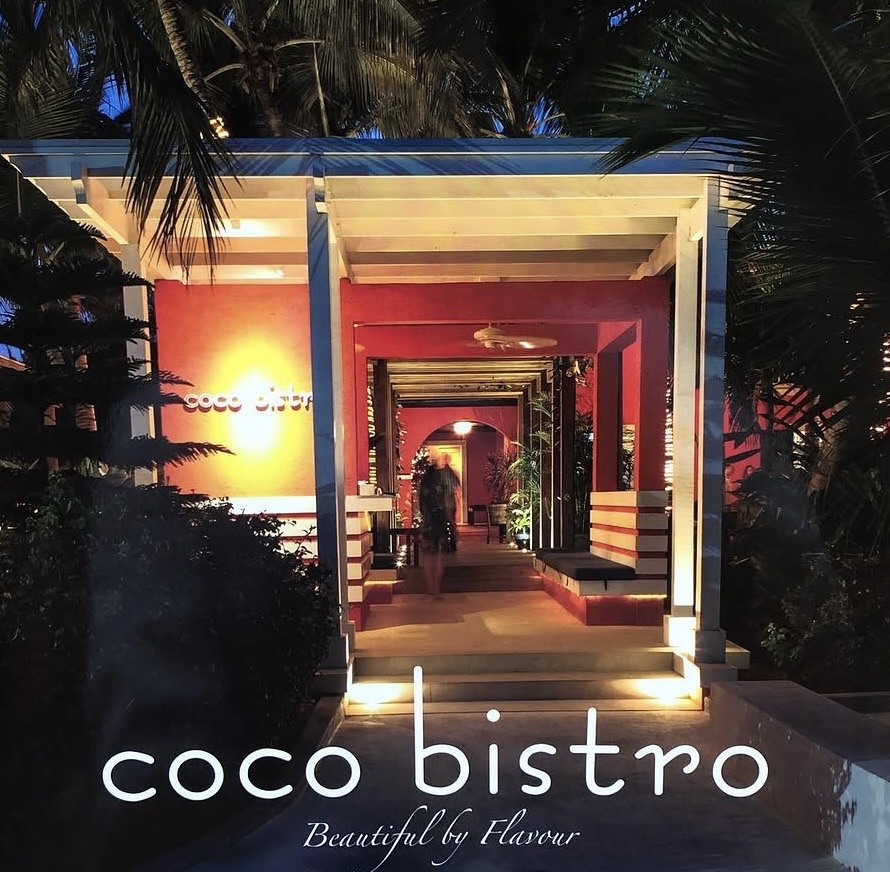 Coco Bistro's lantern-lit entrance at dusk under palm trees