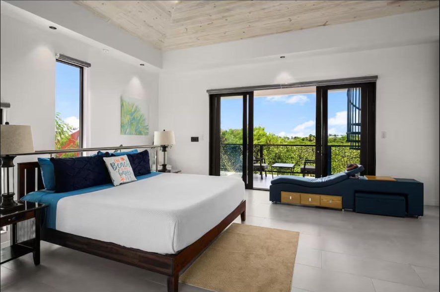 Primary bedroom with king bed and balcony doors to greenery