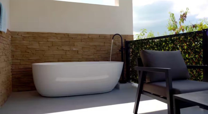 Outdoor freestanding soaking tub on a private stone-walled terrace