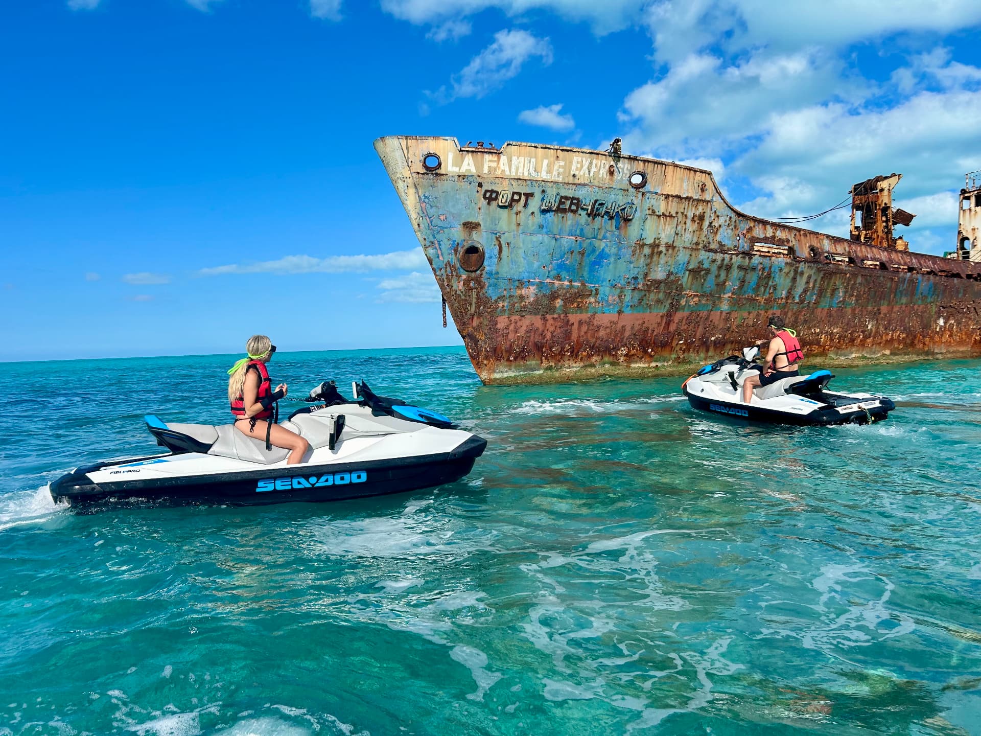 Jet skis beside the La Famille Express shipwreck in turquoise water