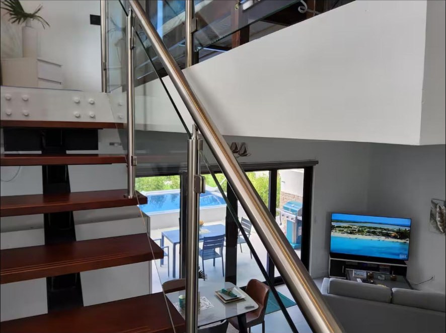 Open living area with glass-railed staircase looking out to the pool deck
